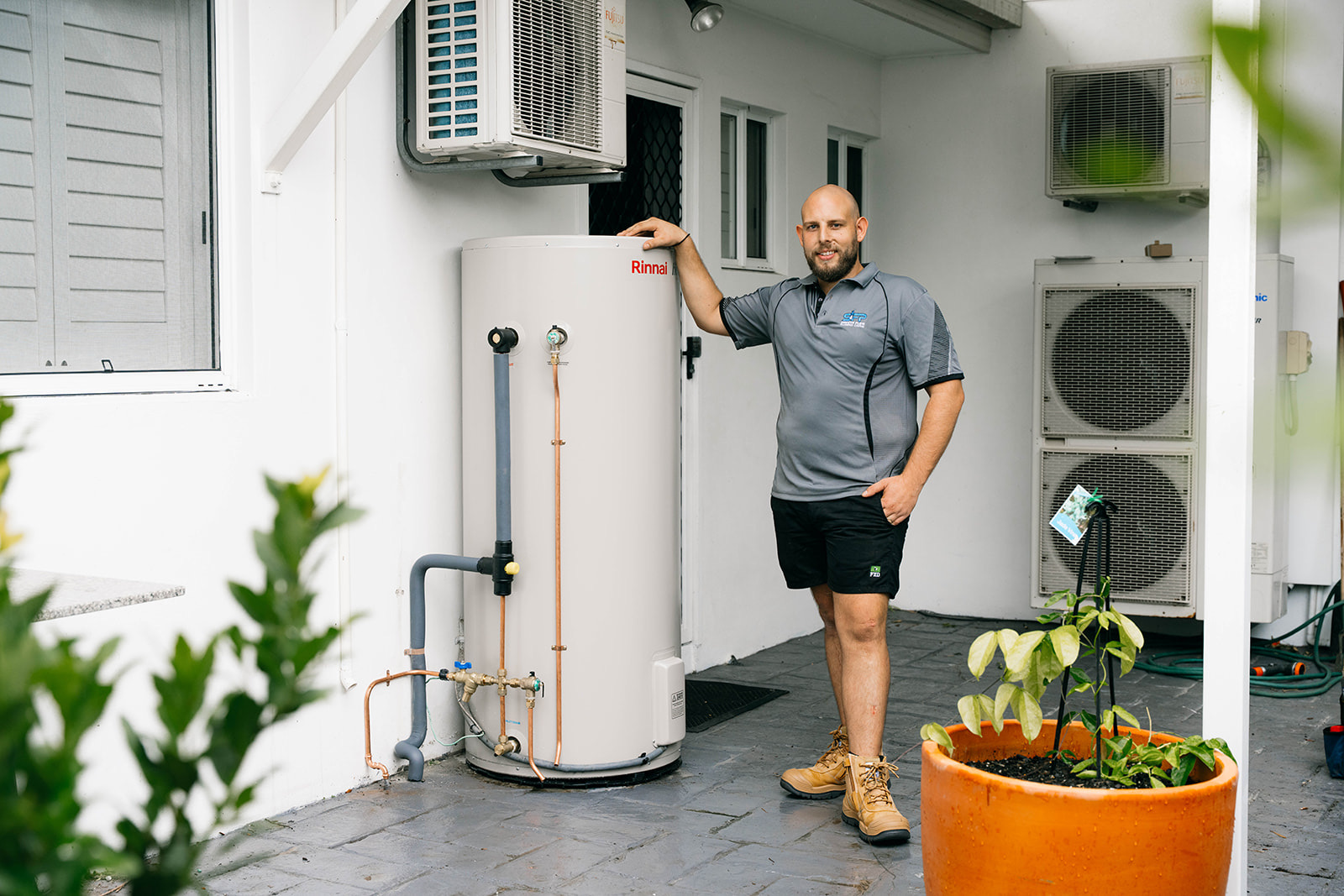 Harris from Smooth Flow Plumbing beside a newly installed hot water system